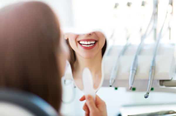 Woman looking at her smile in a mirror in our Concord dental office.